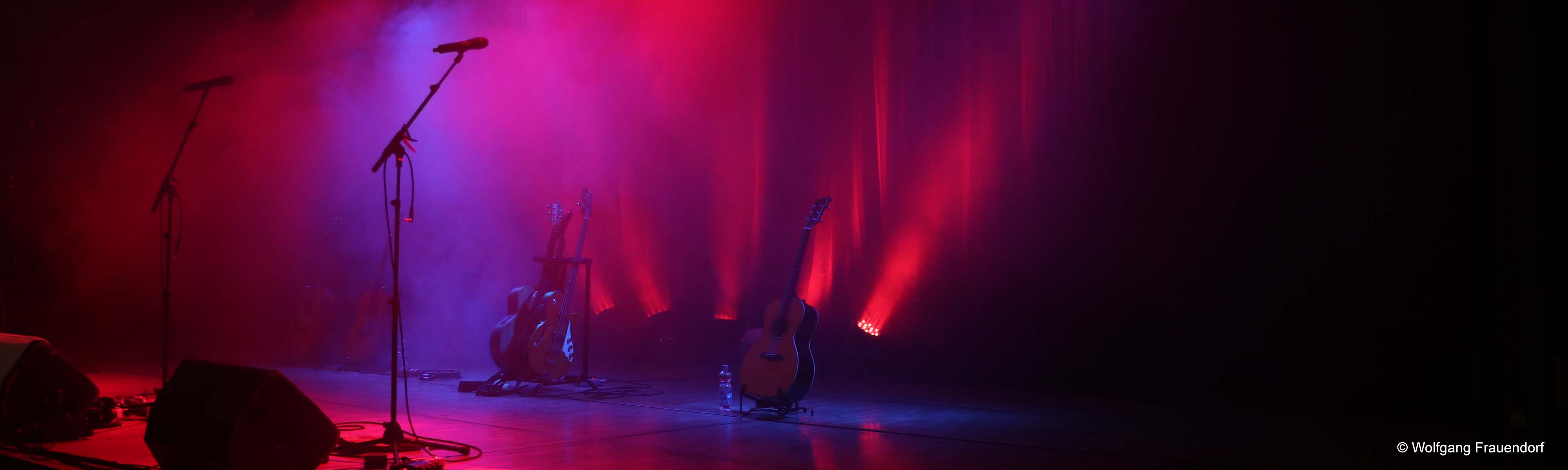 Bühnenbild mit roten Scheinwerfern Gitarren Mikrofone